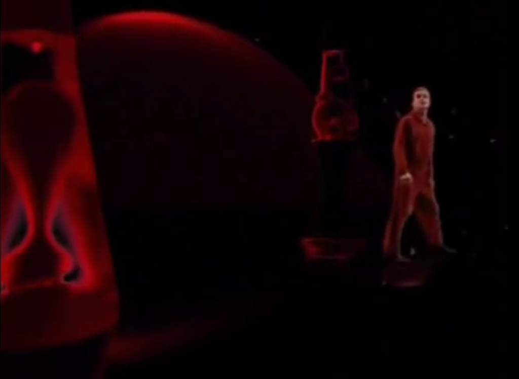 Stan walking by 2 giant red lava lamps with the lava from a third even bigger one floating in the background.