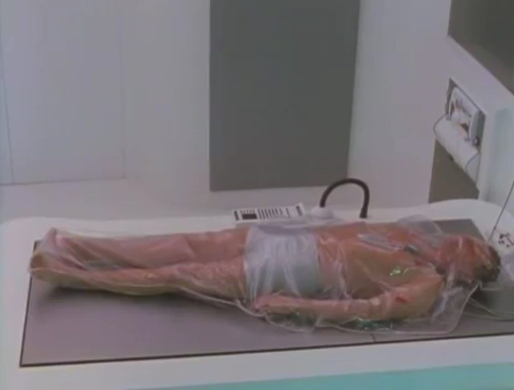 Stan lying on a bed in his boxers while inside a clear bodybag.